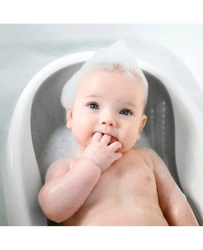 Newborn enjoying his bath with a baby bath support