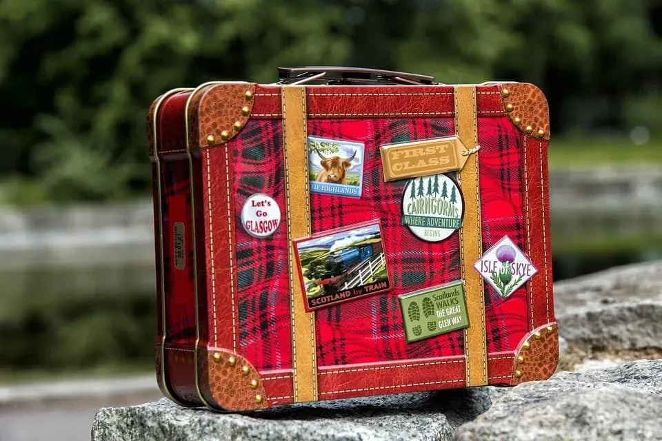 Tartan suitcase with badges of different areas in Scotland stuck on.