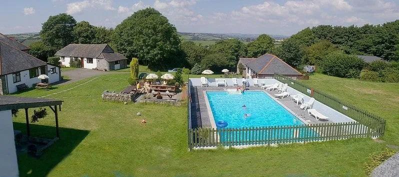 Outdoor pool set in a garden amongst rolling fields at Wringworthy Cottages, Cornwall.