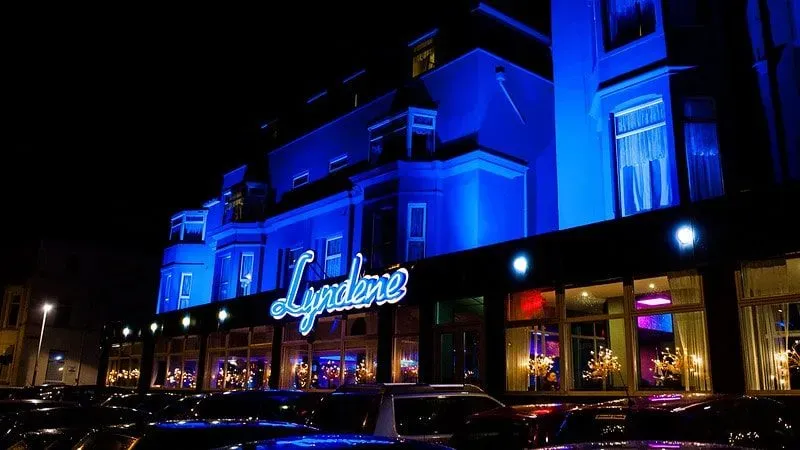Front facade of the Lyndene Hotel, Blackpool, lit up in blue at night.