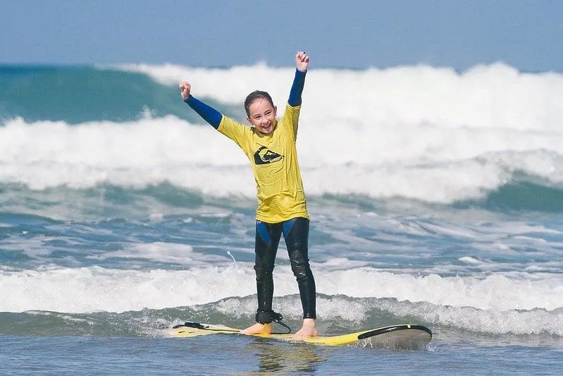 Girl with her hands in the air enjoying her success at paddle-boarding in Newquay.
