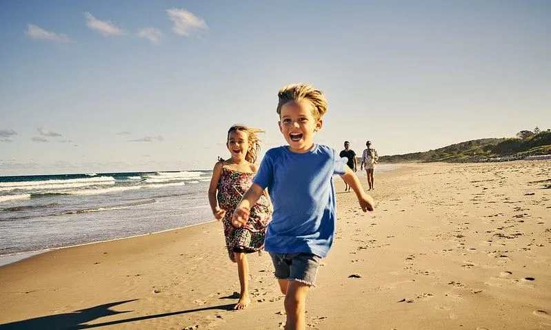 Kids happily running along the beach in Dorset enjoying the perfect family staycation. 
