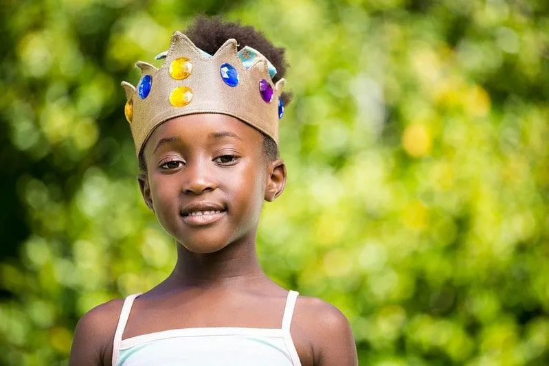 Girl smiling and wearing a crown like a Greek goddess.