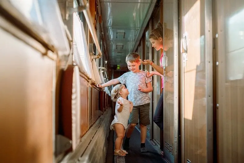 Three children playing and laughing on a train.