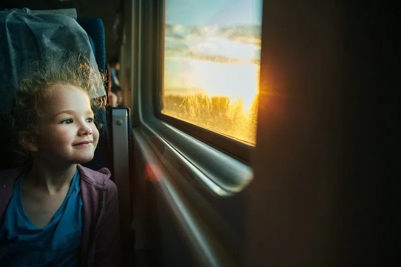 Girl smiling while looking out the train window.