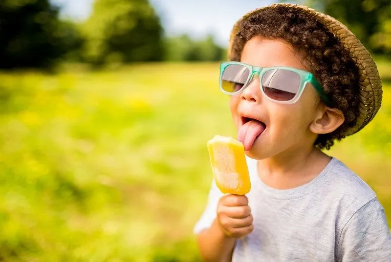 Child licking an ice lolly in a sunny London park