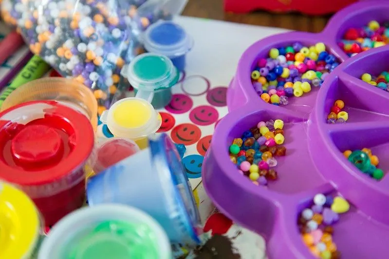 Assorted craft items such as rainbow paint, colourful beads and glitter.