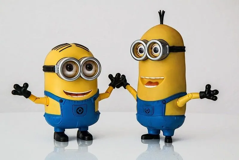 Two minions smiling with their arms outstretched.