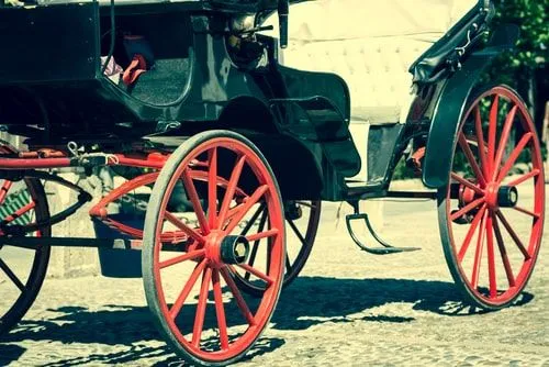 Side view of a Victorian carriage with big red wheels.