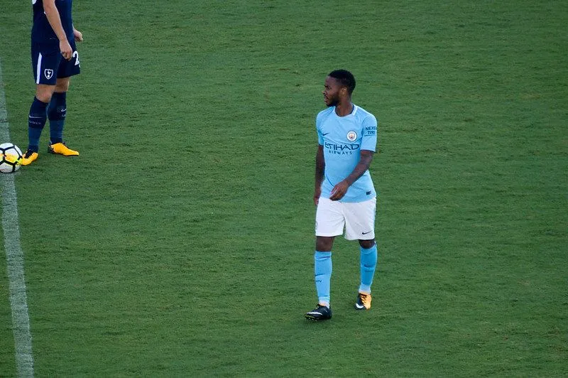 Footballer in blue clothes walking on the field in the middle of a game.