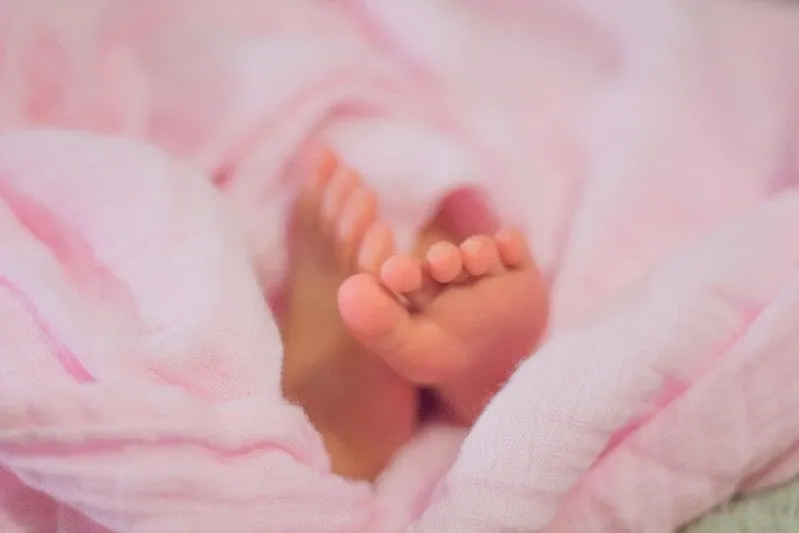 Baby girl's feet poking out a pink blanket.