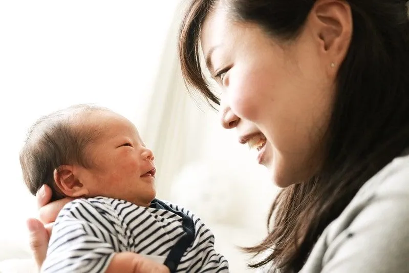Mum and her newborn baby smiling at each other.