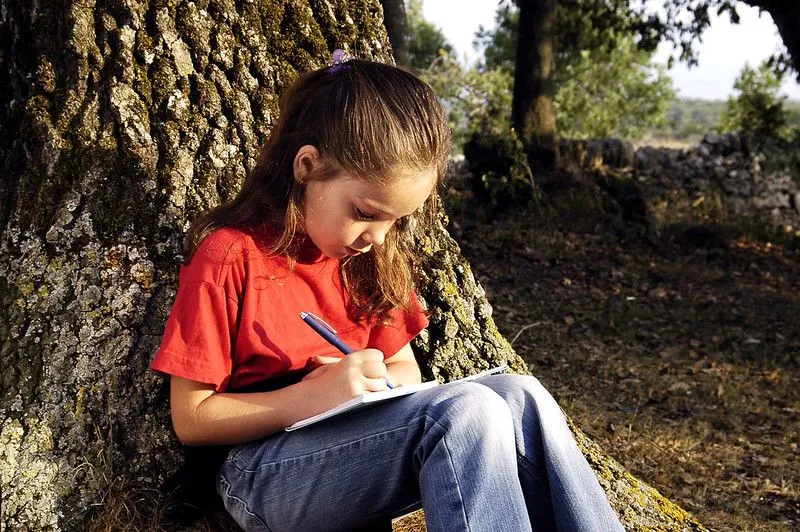 A girl writing in her diary outdoors