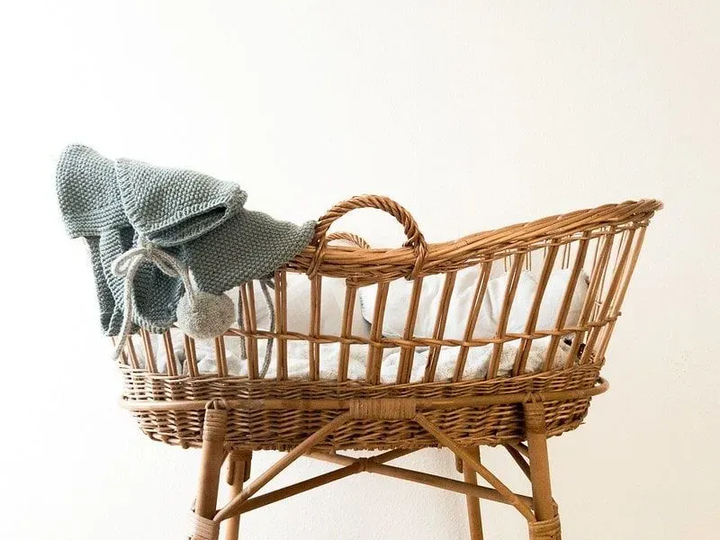 Moses basket with knitted baby outfit draped over the side.