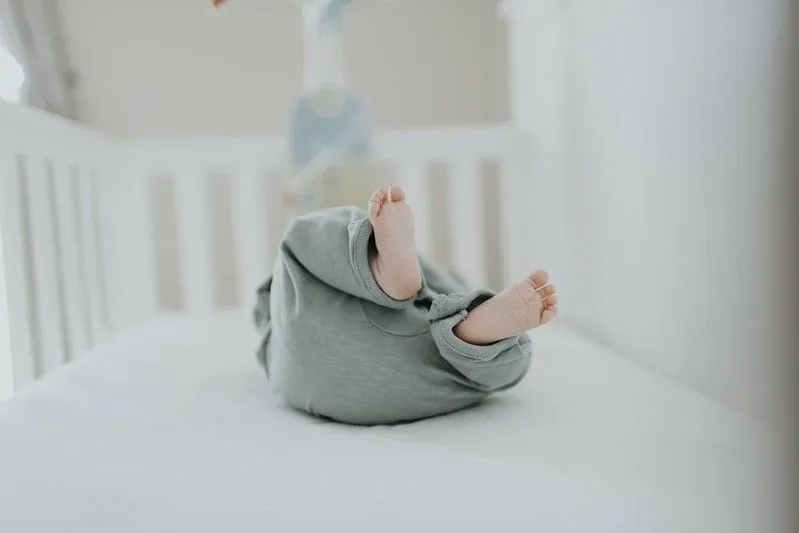 Baby in a crib with its feet in the air.