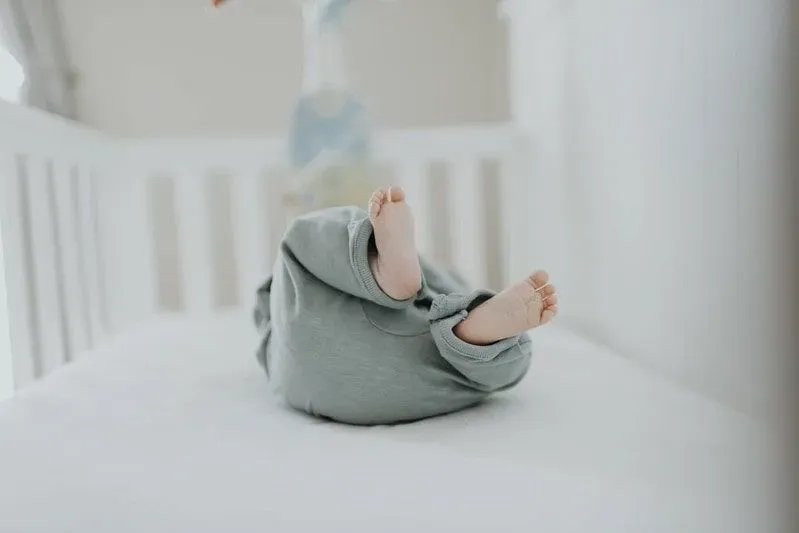 Baby in a crib with its feet in the air.