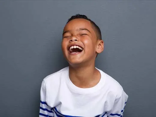 Young boy laughing at a joke.