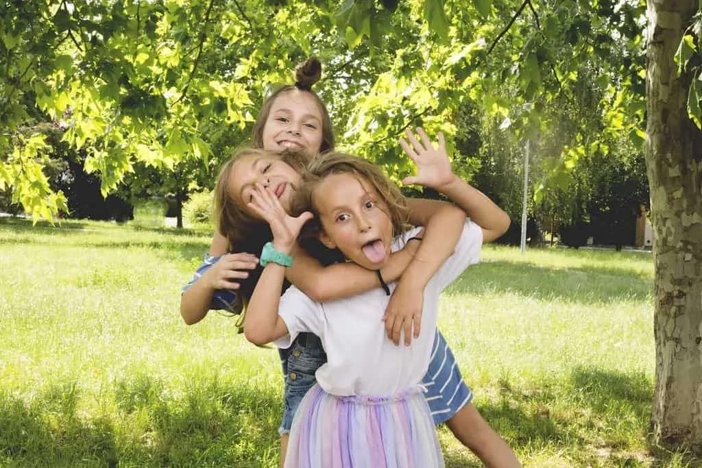 Three girls playing outside making silly faces.