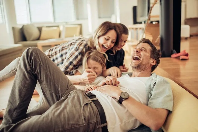 Parents and two children all on the sofa laughing at a joke. 
