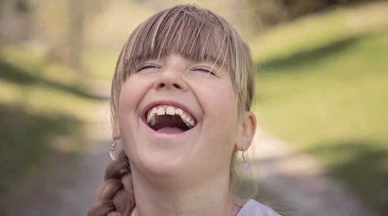 Girl wearing earrings laughing at a joke.