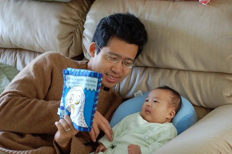 A father is reading a soft book to his baby boy.