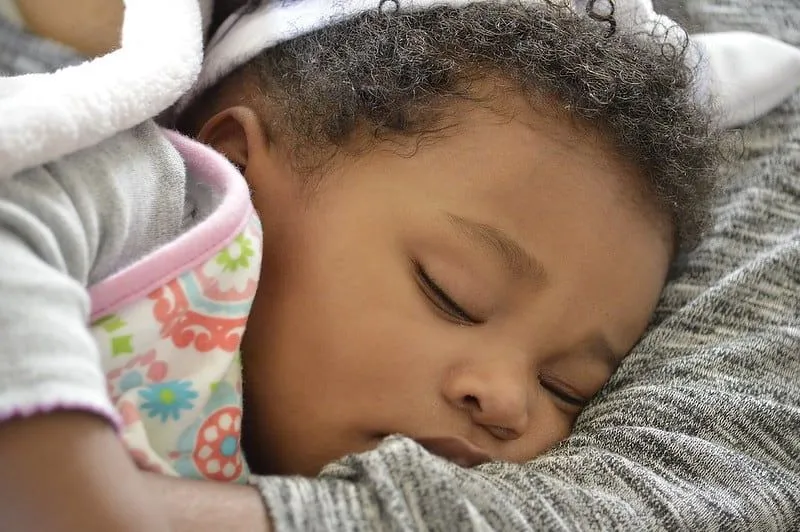 Baby girl sleeping in her mum's arms without a dummy.