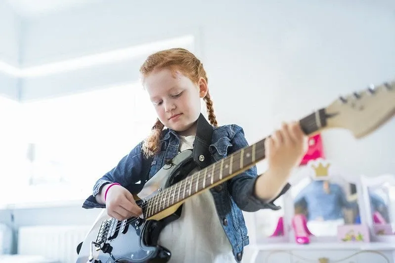 Young girl playing an electric guitar.