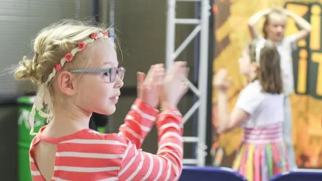 Girl wearing striped top and flower hairband claps.