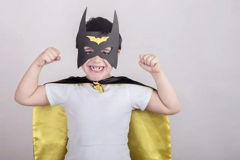 Young boy wearing a homemade batman mask with fists in the air.