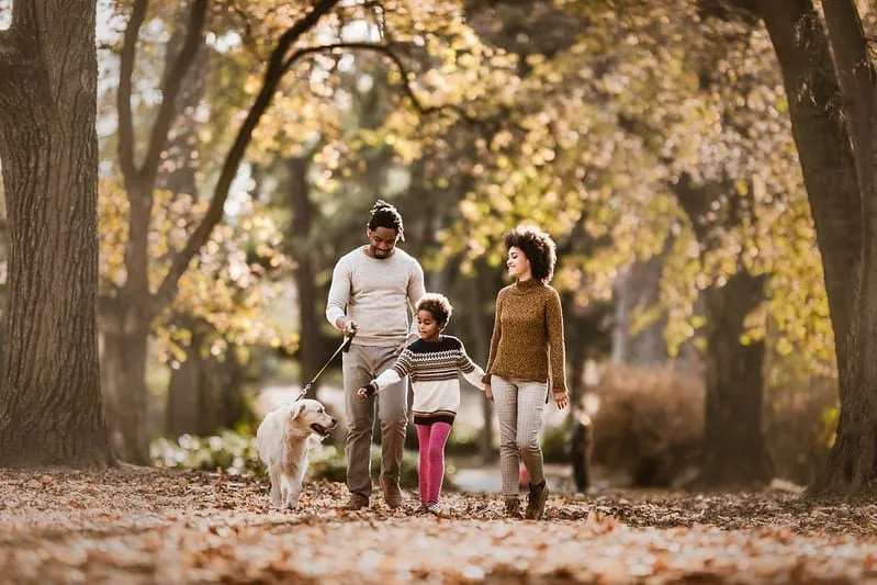 Happy family walking their dog in the park.