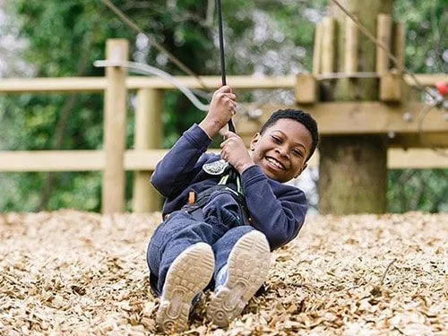 Boy having fun swinging on a rope at Go Ape.