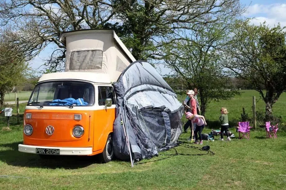 Family setting up their tent from their camper-van.