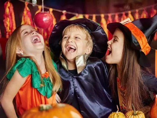 Three kids dressed up in Halloween costumes laughing.