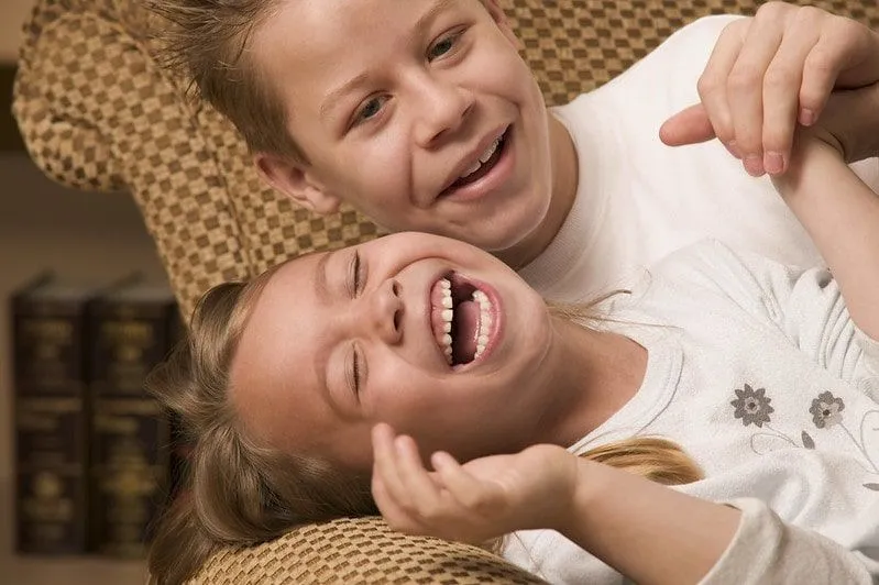 Boy and girl sat together laughing at jokes.