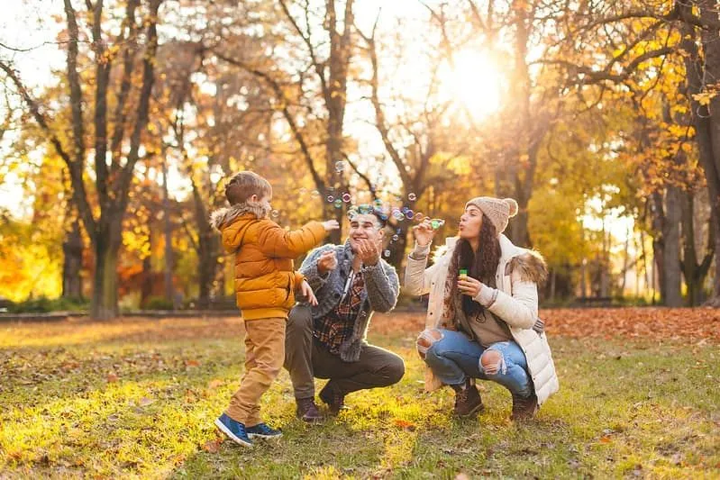 Family out in the park blowing bubbles and enjoying the autumn nature.