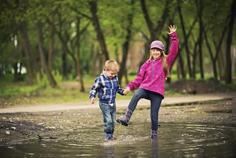 Girl and boy having fun splashing in a puddle.