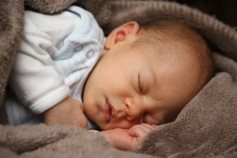 Baby boy sleeping in a brown fleece blanket.