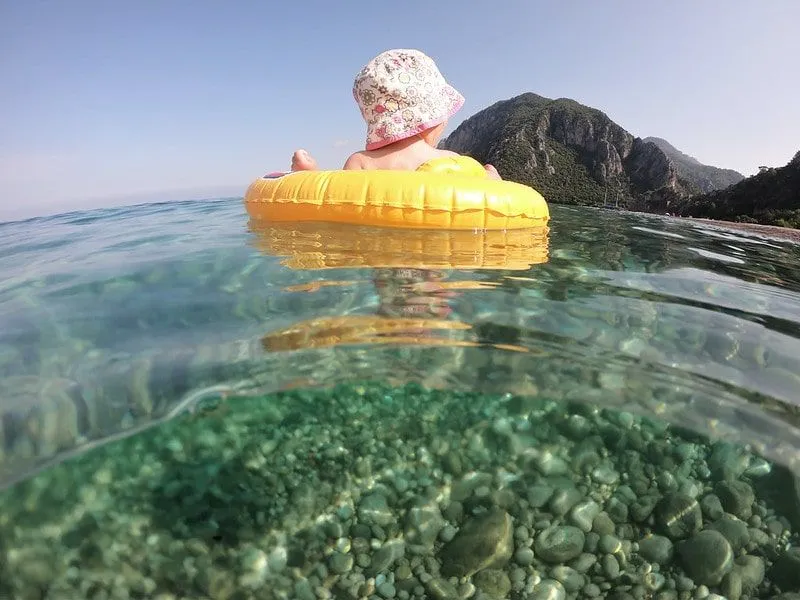 Baby girl in a yellow inflatable ring in floating in the sea.