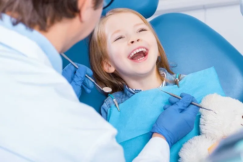 Little girl sitting in the dentist's chair laughing.