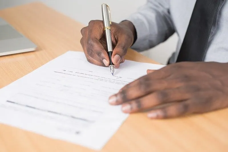 Close up of a dad holding a pen and filling out a form at his desk.