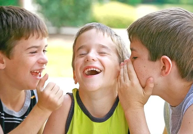 Three boys sharing Spiderman jokes with each other and laughing.