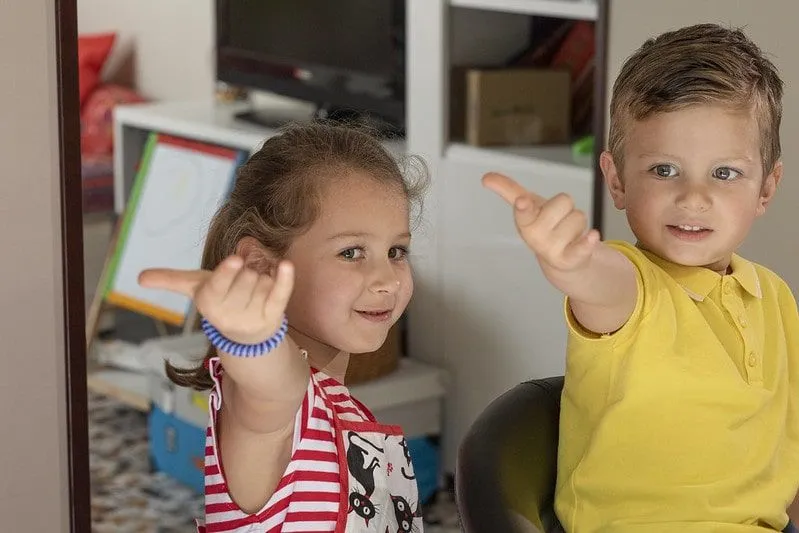 A little girl and boy doing Spiderman hands, pretending to shoot webs from their fingers.