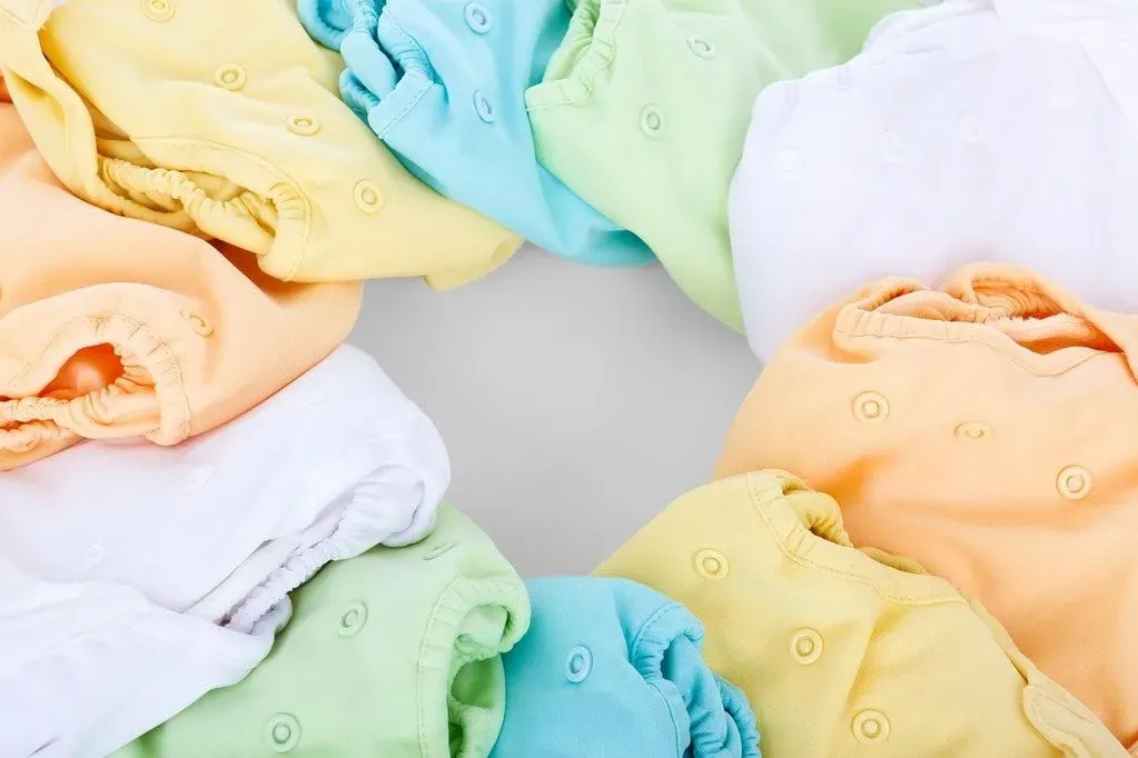 Different colours of folded baby clothes laid out neatly in a circle.