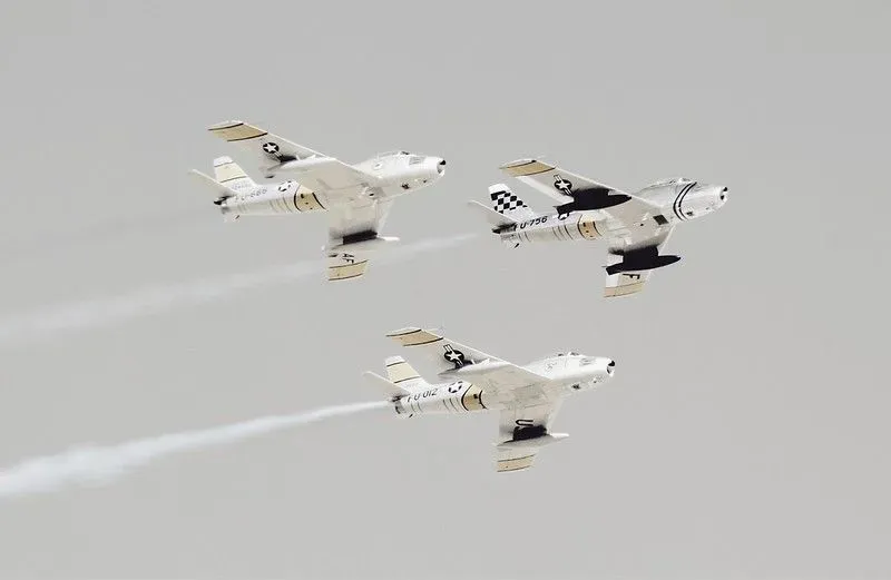 Three black and white planes flying through the air.