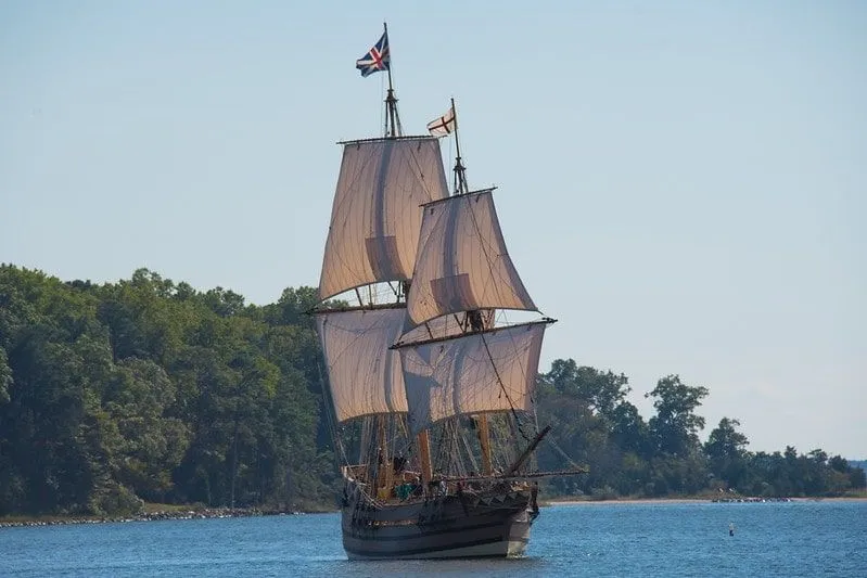 British pirate ship sailing away from an island.