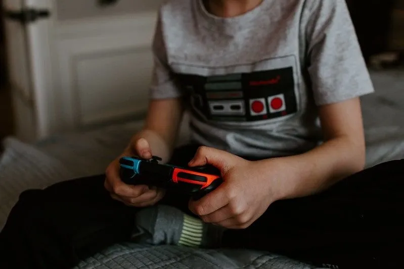 Young boy playing video games on his games console.