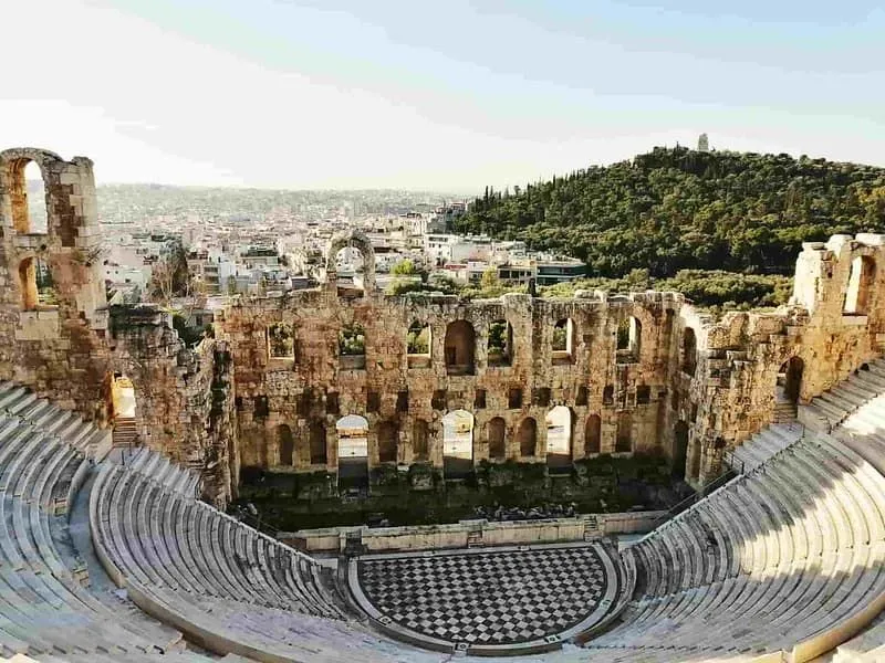 Ancient Greek amphitheatre with a view over the city and a hill.