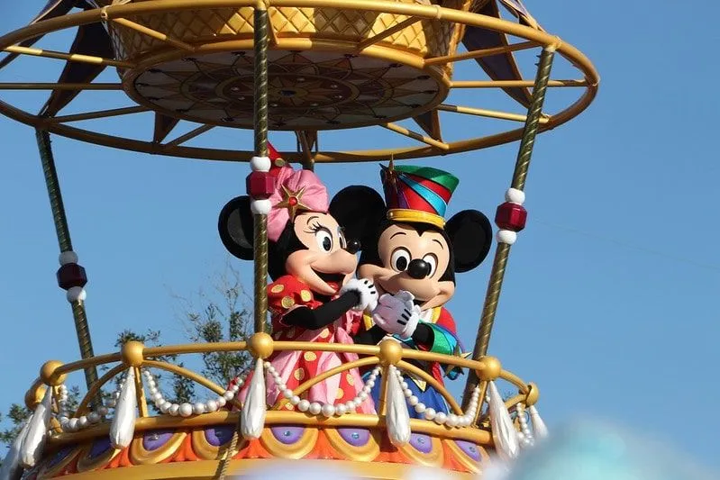 Mickey and Minnie Mouse standing on a parade float waving.