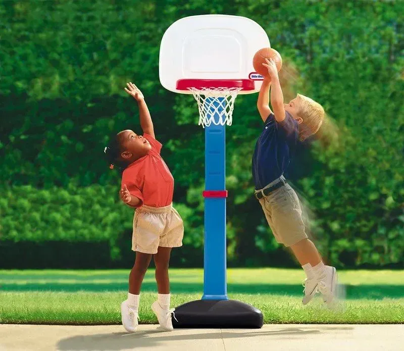 Two children doing a slam dunk in a children's basketball hoop.