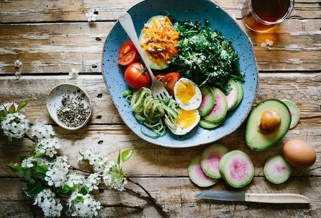 Yummy looking plate of vegetarian food and an avocado on the side.